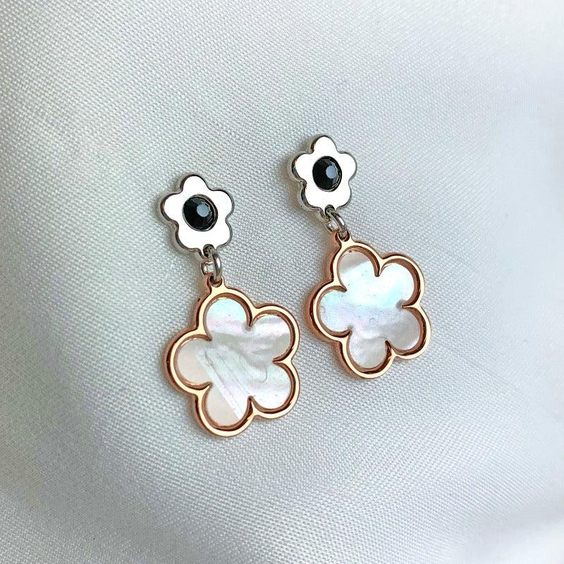 These stunning earrings showcase a 18-carat rose gold-plated Mother of Pearl flower delicately suspended from a small sterling silver flower embellished with Onyx.    With their intricate design and attention to detail, they capture the essence of Jane Austen's beloved novel, Pride and Prejudice. 