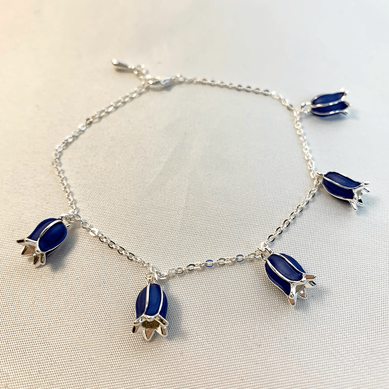 The bluebell bracelet is laid out to show each of the 5 individual bluebell flowers that are attached to the chain. making it a beautiful spring gift 