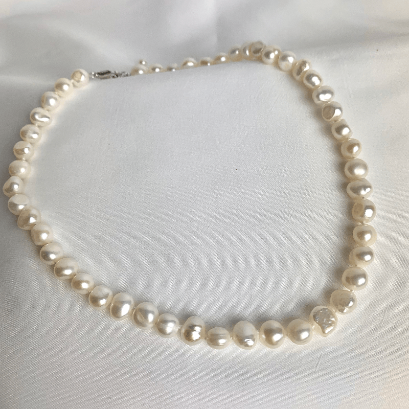 Jane Bennet Pearl Necklace. A string of natural freshwater pearls on display with the lobster claw clasp
